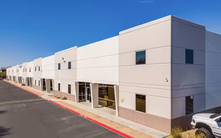 White building at Sonoran Junction beside a paved driveway.