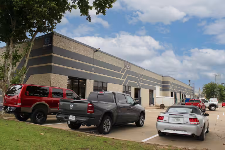 Long industrial building at Marquis Drive with vehicles parked in front.